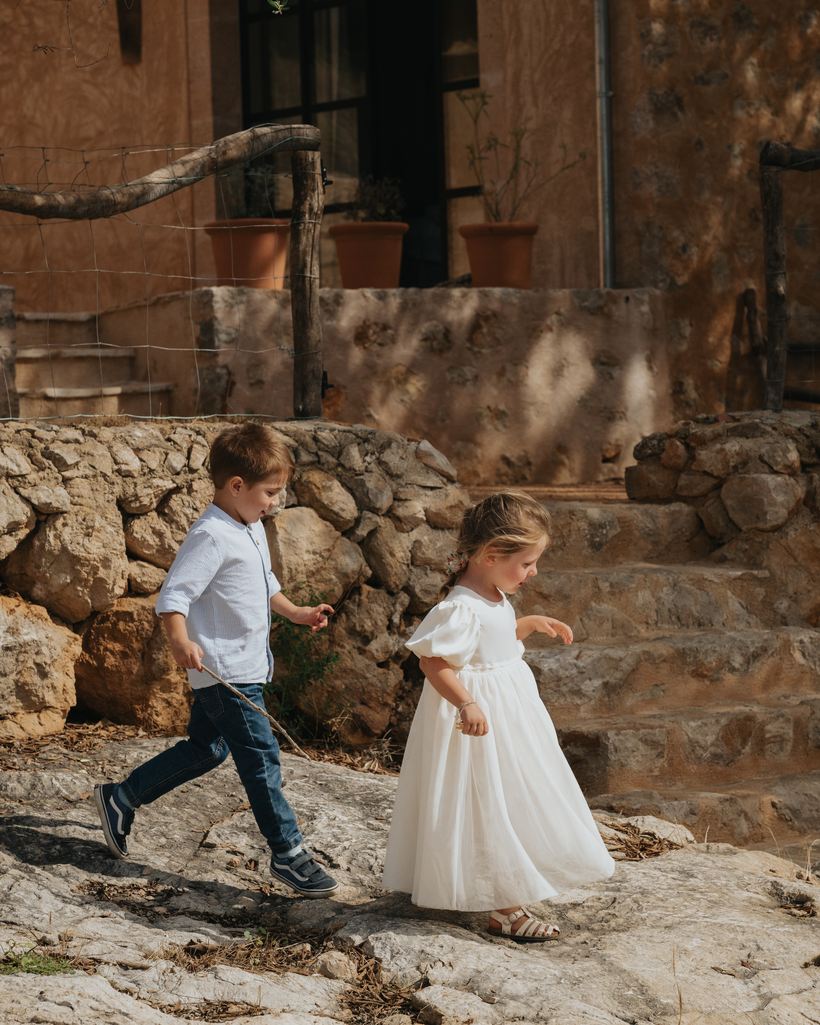 Dos niños caminan sobre la roca ante la casa de piedra de TERRA